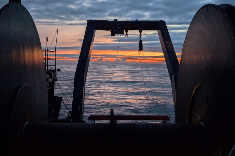 Sunset through net reel of research vessel